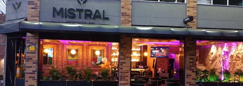 Fachada de Mistral, restaurante y bar, de noche, con ladrillo y luz cálida